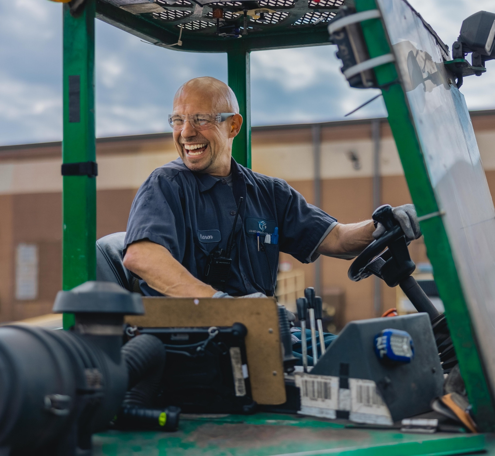 Employee smiles as he moves grating products indoors using a forklift