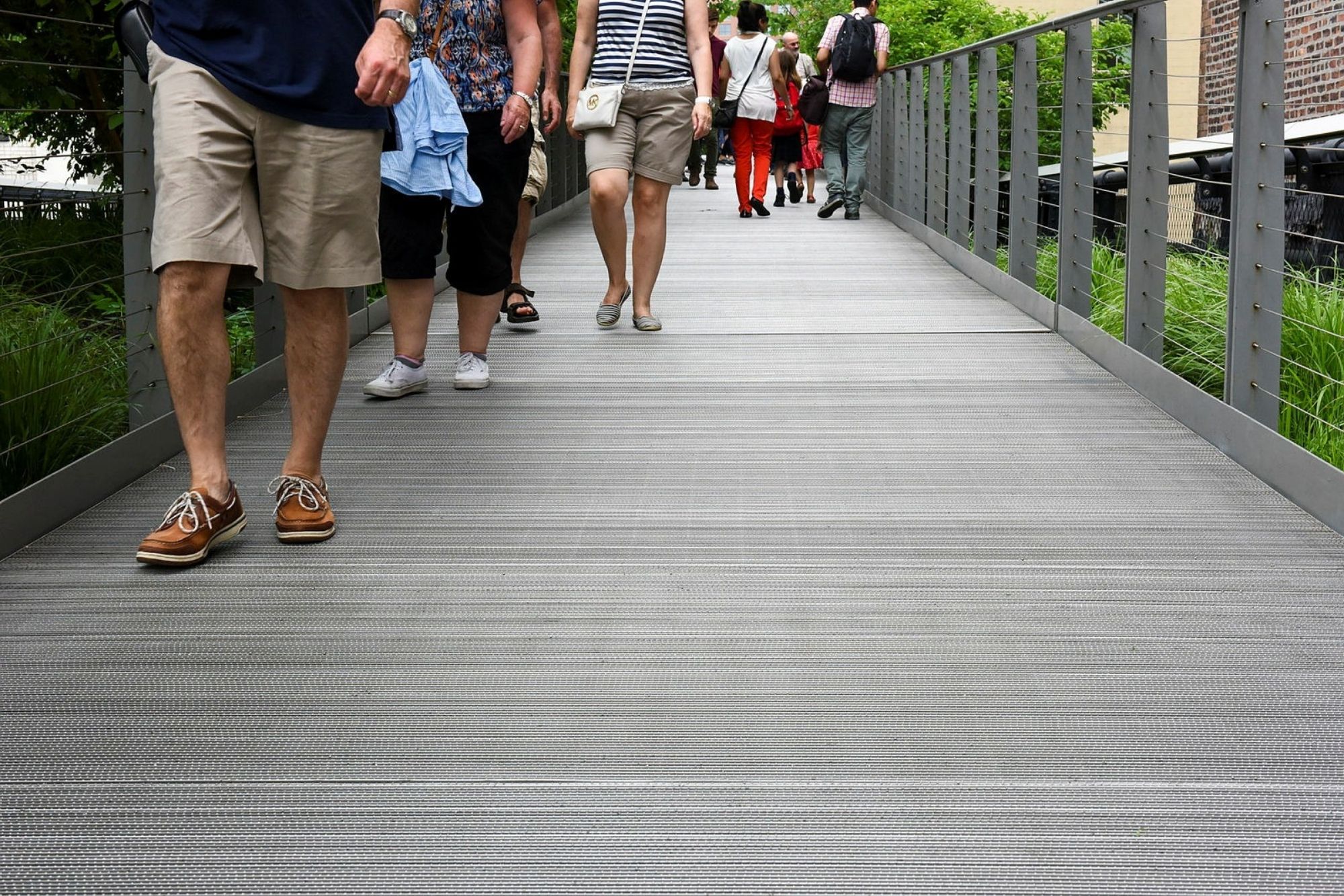 Pedestrians utilize grating bridge at Highline Park in New York